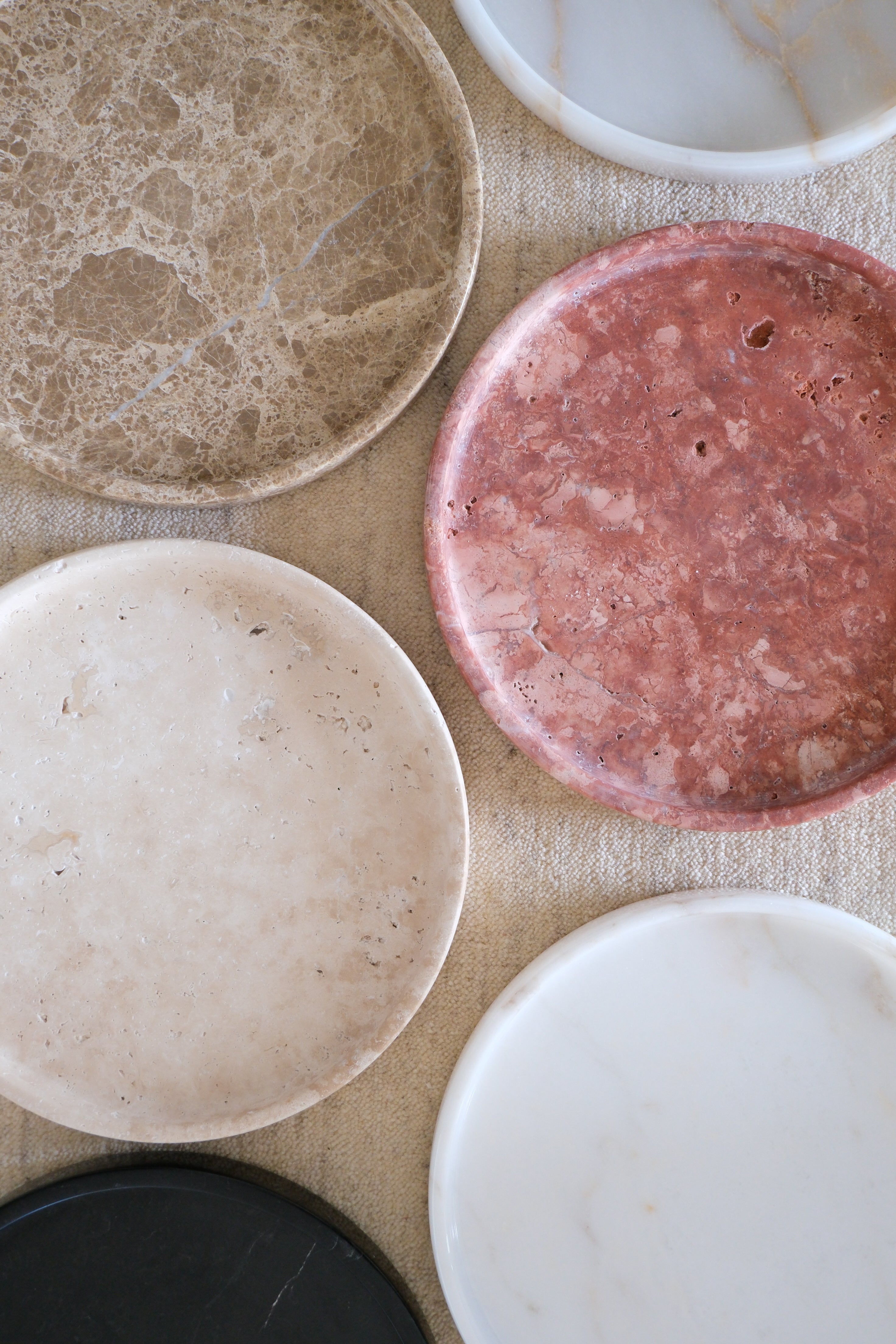 Collection of six Raya marble trays in various colors, showcasing their elegant round design and polished finish.